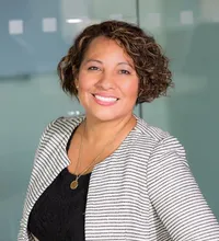 Smiling woman with curly hair in a professional striped blazer