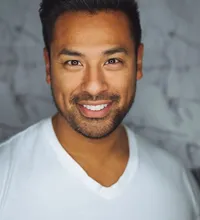 Friendly man with short dark hair smiling in a white v-neck