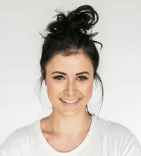 Young woman with dark hair in a bun smiling warmly